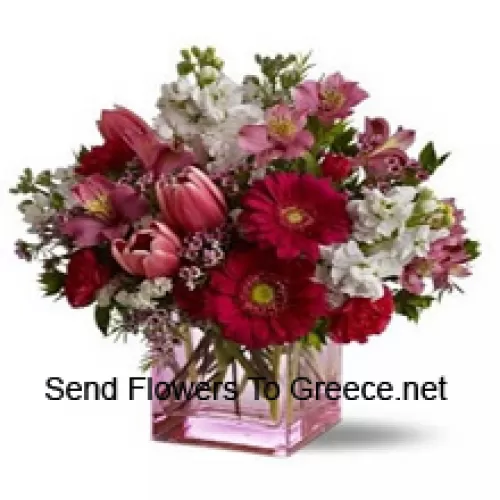 Rosas rojas, tulipanes rojos y flores surtidas con rellenos de temporada dispuestas hermosamente en un jarrón de cristal