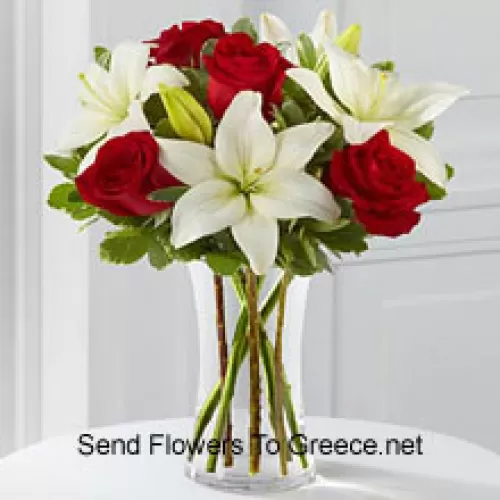 الورود الحمراء والزنابق البيضاء مع بعض الملء الموسمي في مزهرية زجاجية